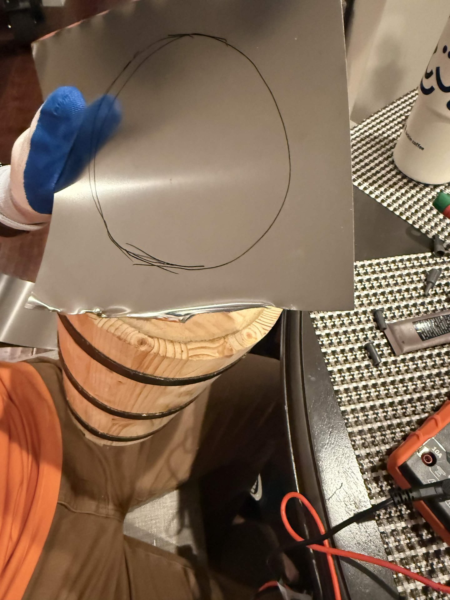 A circular contact shape marked on sheet metal above the wooden barrel